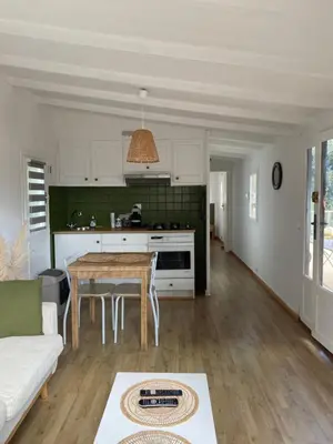 a living room with a table and a kitchen at Petit chalet d’été avec piscine privée chauffée in Bonifacio