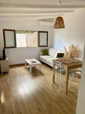a living room with a table and a couch at Petit chalet d’été avec piscine privée chauffée in Bonifacio