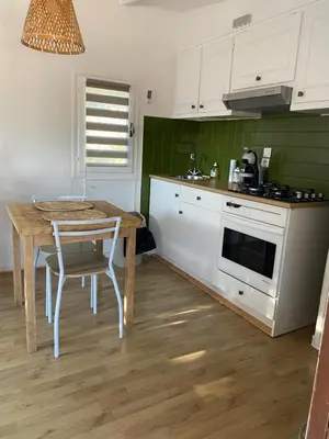 a kitchen with a wooden table and a table and a stove at Petit chalet d’été avec piscine privée chauffée in Bonifacio