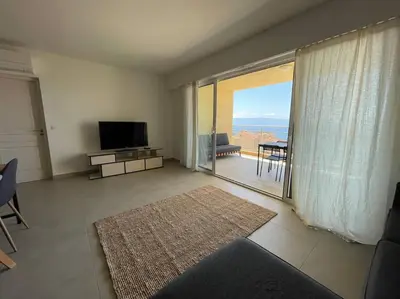 a living room with a television and a view of the ocean at Appartement T3 face à la mer in Ajaccio