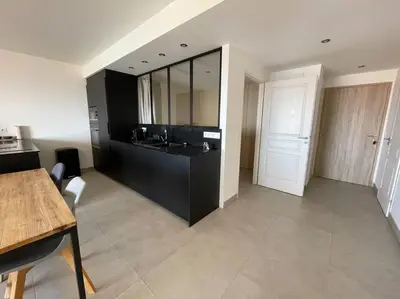 a large kitchen with a black counter and a table at Appartement T3 face à la mer in Ajaccio