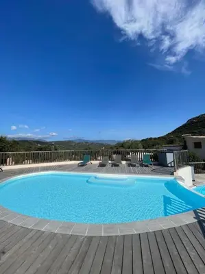 a swimming pool on a wooden deck with a blue sky at Appartement & Piscine Santa Giulia in Porto-Vecchio
