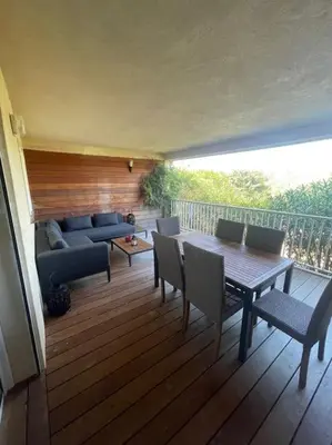 a deck with a couch and a table and chairs at Appartement & Piscine Santa Giulia in Porto-Vecchio
