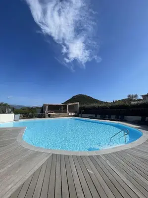 a large blue swimming pool on a wooden deck at Appartement & Piscine Santa Giulia in Porto-Vecchio