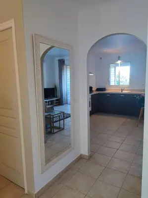 a living room with a mirror and a kitchen at Appartement & Piscine Santa Giulia in Porto-Vecchio