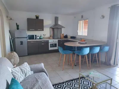 a kitchen with a table and some blue chairs at Appartement & Piscine Santa Giulia in Porto-Vecchio