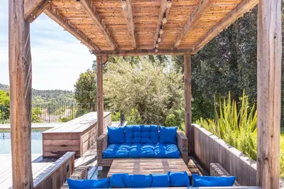 a wooden pergola with blue couches on a deck at Villa U Meribellu Di Santa Lucia in Sainte-Lucie de Porto-Vecchio
