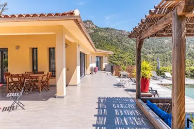 a house with a deck with a table and chairs at Villa U Meribellu Di Santa Lucia in Sainte-Lucie de Porto-Vecchio