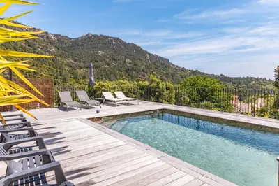 a swimming pool with chairs and a mountain in the background at Villa U Meribellu Di Santa Lucia in Sainte-Lucie de Porto-Vecchio