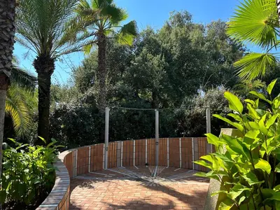 a fence in a garden with palm trees at Résidence les chênes in Borgo