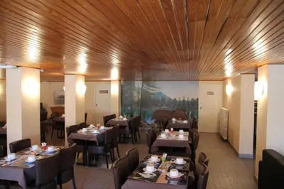 a restaurant with wooden ceilings and tables and chairs at Hôtel Sampiero Corso in Corte
