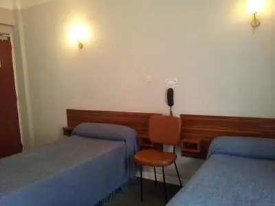 a hotel room with two beds and a chair at Hôtel Sampiero Corso in Corte