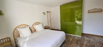 a bedroom with a white bed and a green wall at Villa de standing Les Amandiers, vue mer & piscine in Propriano