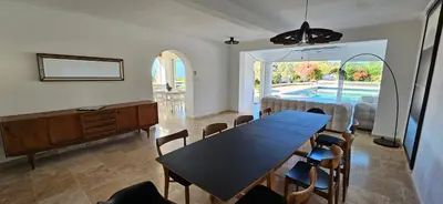 a dining room with a table and chairs and a pool at Villa de standing Les Amandiers, vue mer & piscine in Propriano