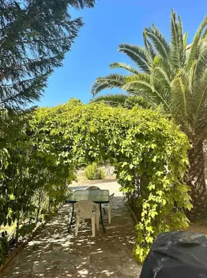 a table and chairs sitting under an arch with trees at Appartement en rez de villa in Aregno