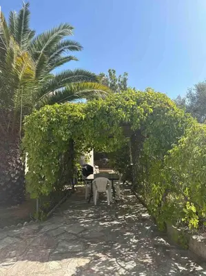 a patio with a table and chairs under a hedge at Appartement en rez de villa in Aregno