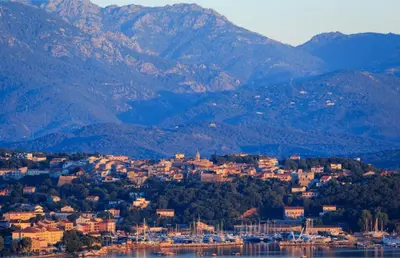 a town on the shore of a lake with mountains at Villa Baccarat in Porto-Vecchio