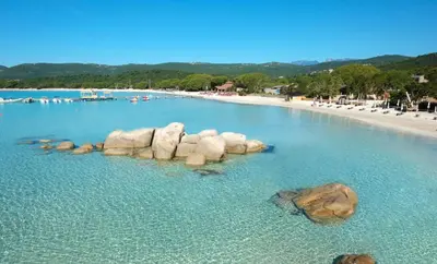 a pool with rocks in the water next to a beach at Villa Baccarat in Porto-Vecchio