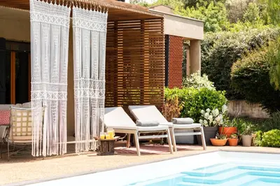 a pool with two chairs and a table next to a house at Villa Baccarat in Porto-Vecchio