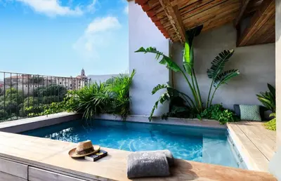a swimming pool with a hat sitting on a table next to a building at Penthouse Les Oliviers in Porto-Vecchio