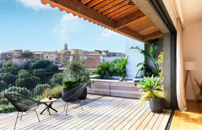 a deck with chairs and a table on a balcony at Penthouse Les Oliviers in Porto-Vecchio