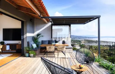 a patio with a table and chairs on a deck at Penthouse Les Oliviers in Porto-Vecchio
