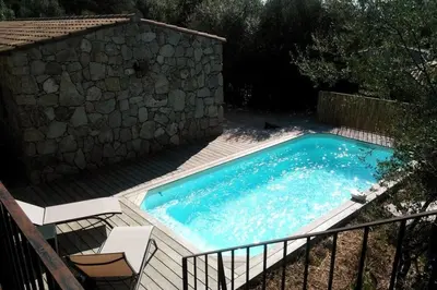 a swimming pool with two chairs and a stone wall at Bergerie Nepita Oasis Rustique and Private Pool in Porto-Vecchio