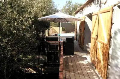 a patio with an umbrella and a table and chairs at Bergerie Nepita Oasis Rustique and Private Pool in Porto-Vecchio