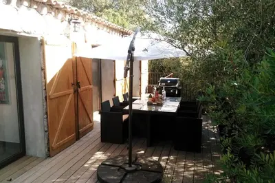 a black desk on a patio with an umbrella at Bergerie Nepita Oasis Rustique and Private Pool in Porto-Vecchio