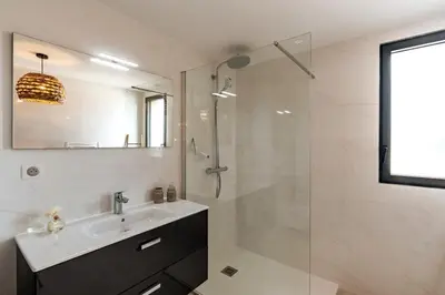 a bathroom with a sink and a glass shower at Superb flat with a lovely view of the mountains in Porto-Vecchio