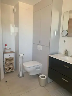 a white bathroom with a toilet and a sink at Superb flat with a lovely view of the mountains in Porto-Vecchio