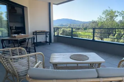 a balcony with a table and chairs and a large window at Superb flat with a lovely view of the mountains in Porto-Vecchio