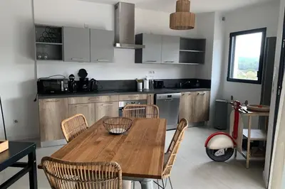 a kitchen with a wooden table and some chairs at Superb flat with a lovely view of the mountains in Porto-Vecchio
