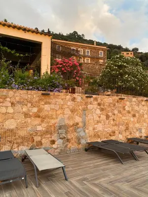 a stone wall with two chairs and a table at Gîte A Funtana Montestremo, Balagne, Haute Corse in Manso
