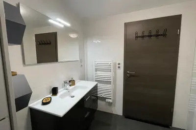 a bathroom with a sink and a brown door at Two-bedroom flat with terrace near the harbour and town centre in Porto-Vecchio