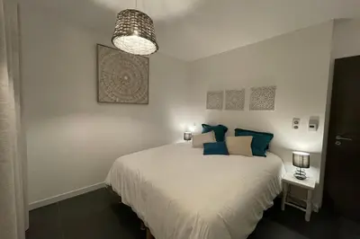 a bedroom with a white bed with blue pillows at Two-bedroom flat with terrace near the harbour and town centre in Porto-Vecchio