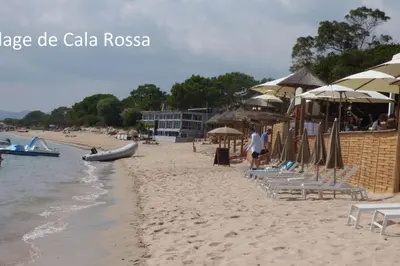 a sandy beach with chairs and umbrellas and the ocean at Rez de jardin dans une résidence de charme ... in Porto-Vecchio