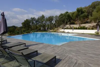 a swimming pool with chairs and an umbrella at Rez de jardin dans une résidence de charme ... in Porto-Vecchio