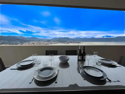 a white table with plates and wine glasses and a large window at Les terrasses de Toretta in Ajaccio