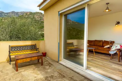 a patio with a bench and a couch on a balcony at SEJOUR DETENTE BALAGNE ENTRE MER ET MONTAGNE in Urtaca