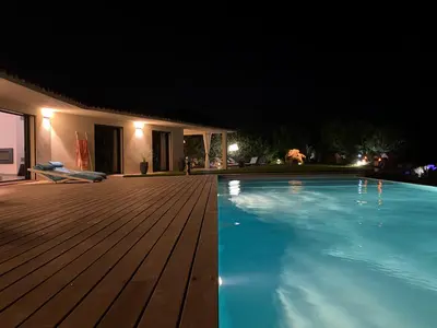 a swimming pool at night with a wooden deck at VILLA SANTA GIULIA 240M2 CLASSEE 5 étoiles Vue Mer 180 degrès in Porto-Vecchio
