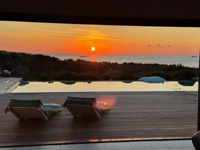 two chairs on a deck with a sunset in the background at VILLA SANTA GIULIA 240M2 CLASSEE 5 étoiles Vue Mer 180 degrès in Porto-Vecchio