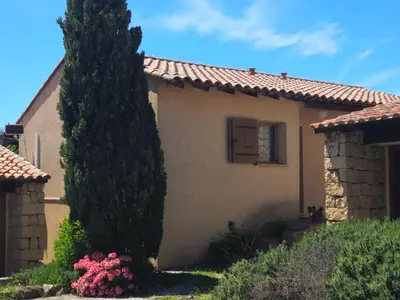 a house with a large tree next to a building at Villa 78 Alba Rossa Piscine chauffée et Plage de Cupabia in Serra-di-Ferro