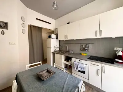a kitchen with white cabinets and a table in it at Casamea - Escapade en bord de mer, Accès plage in Ajaccio
