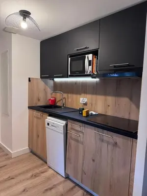 a kitchen with black cabinets and a microwave at Appartement à Cala Rossa in Lecci