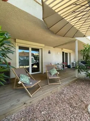 two chairs sitting on a wooden deck in front of a house at Appartement à Cala Rossa in Lecci