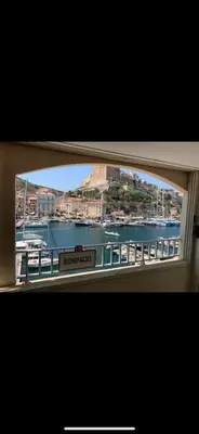 a window with a view of a river and a city at Sur le port face à la citadelle in Bonifacio