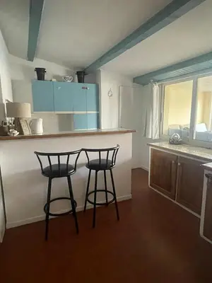 a kitchen with two bar stools and a counter at Sur le port face à la citadelle in Bonifacio