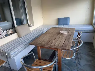 a wooden table and chairs in a room with a bed at Sur le port face à la citadelle in Bonifacio
