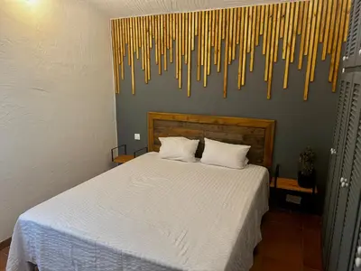 a bedroom with a bed with white sheets and some pasta hanging from the wall at Villa l'Albizia accès privé rivière in Porto-Vecchio